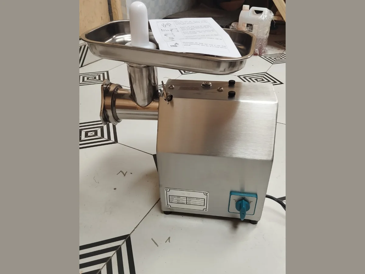 Mincer 12 Stainless steel electric meat mincer with feed tray and mincing head, labelled TK-12