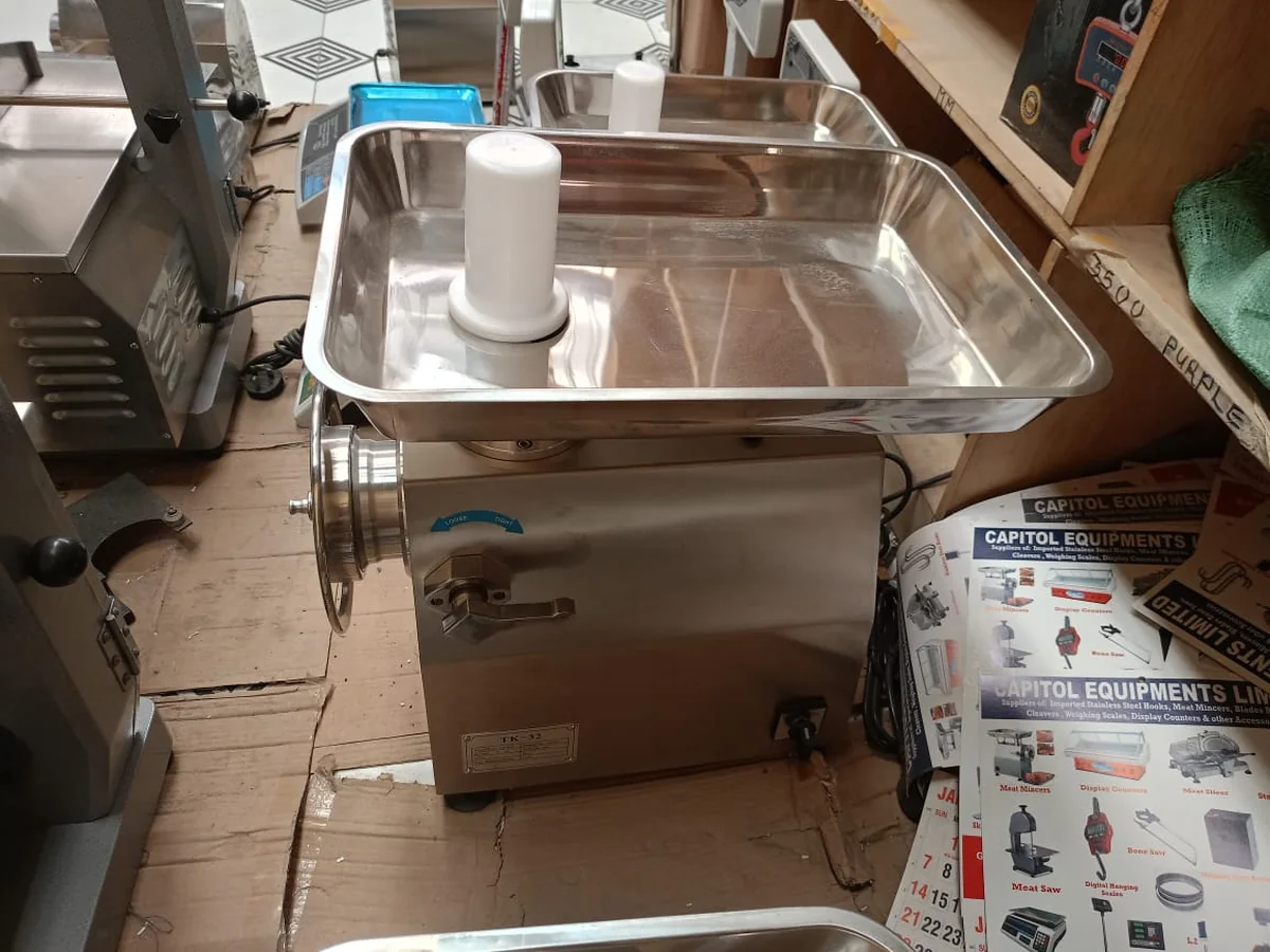 Stainless steel electric meat mincer with large feed tray on the shop bench, labelled TK-32